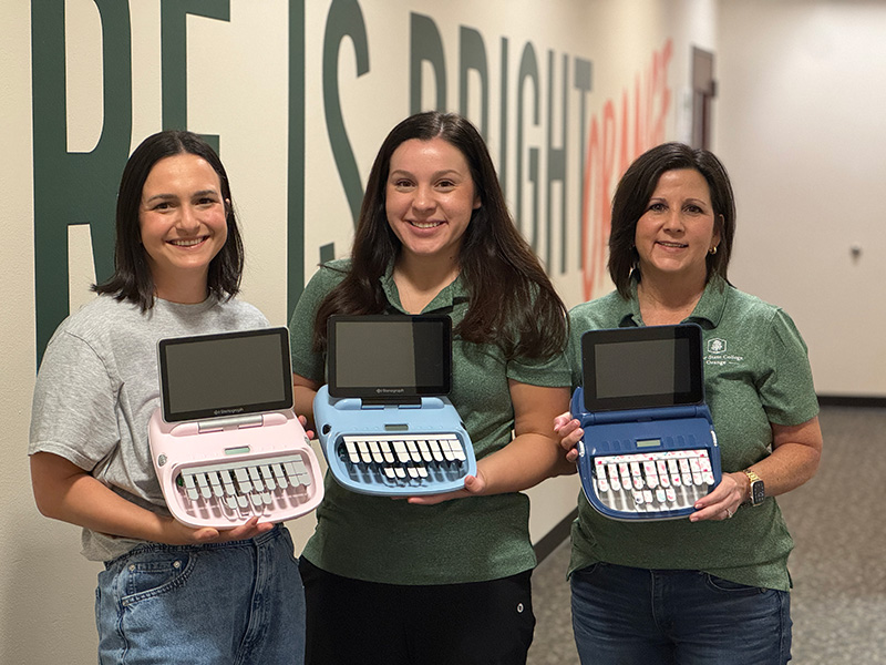 court reporting student and faculty holding steno writers
