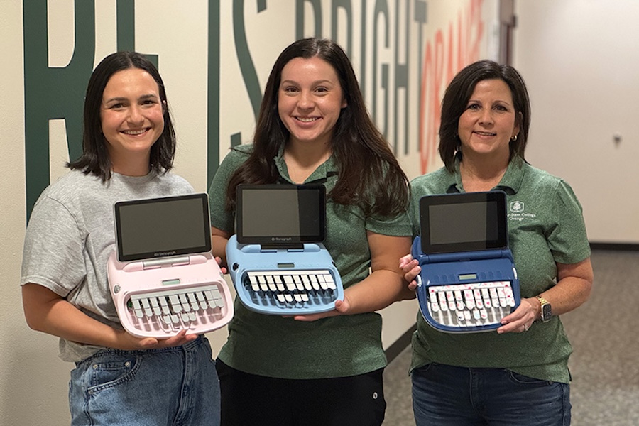 court reporting student and faculty holding steno writers