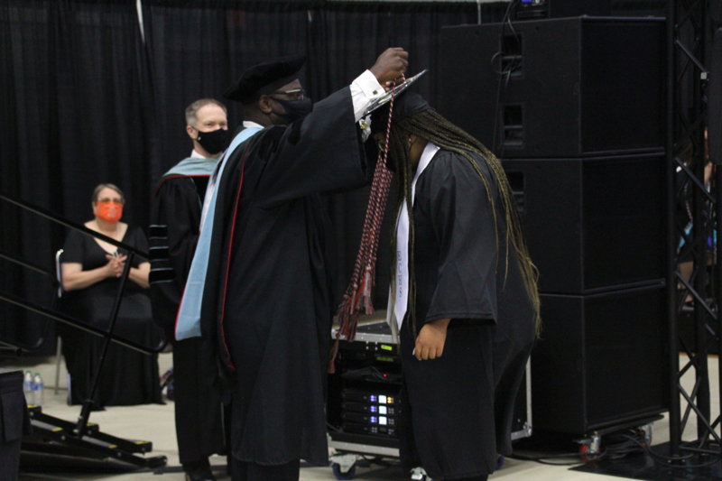Dr. Rickie Harris places ECHS cord over graduating student